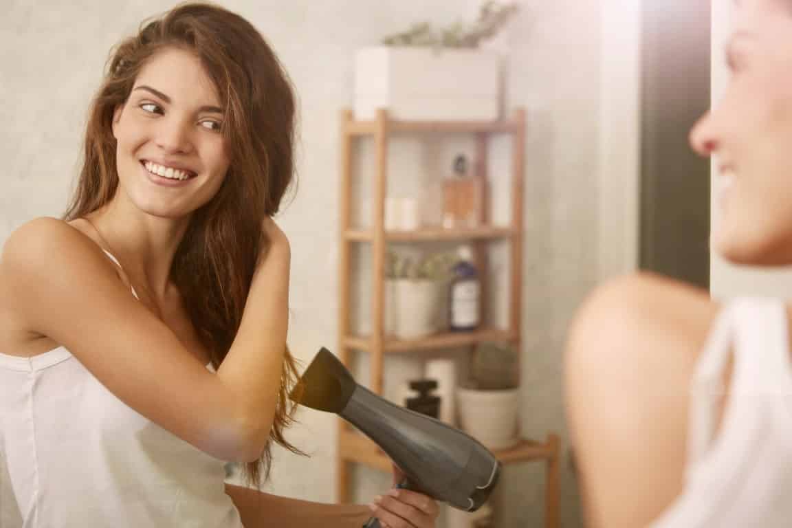 Femme se séchant les cheveux et préparant un brushing wavy