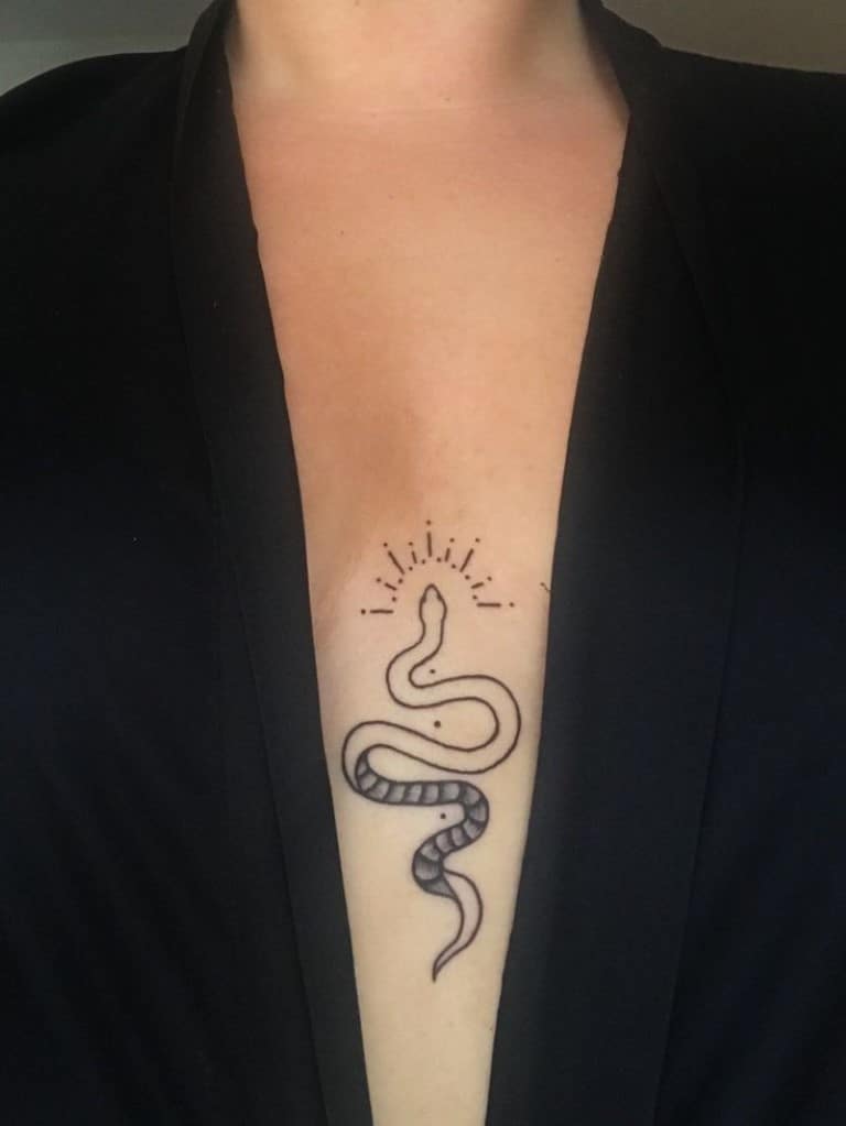 Un serpent minimaliste tatoué entre les seins