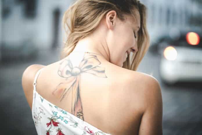 Femme possédant un tatouage sur le haut de la colonne vertébrale